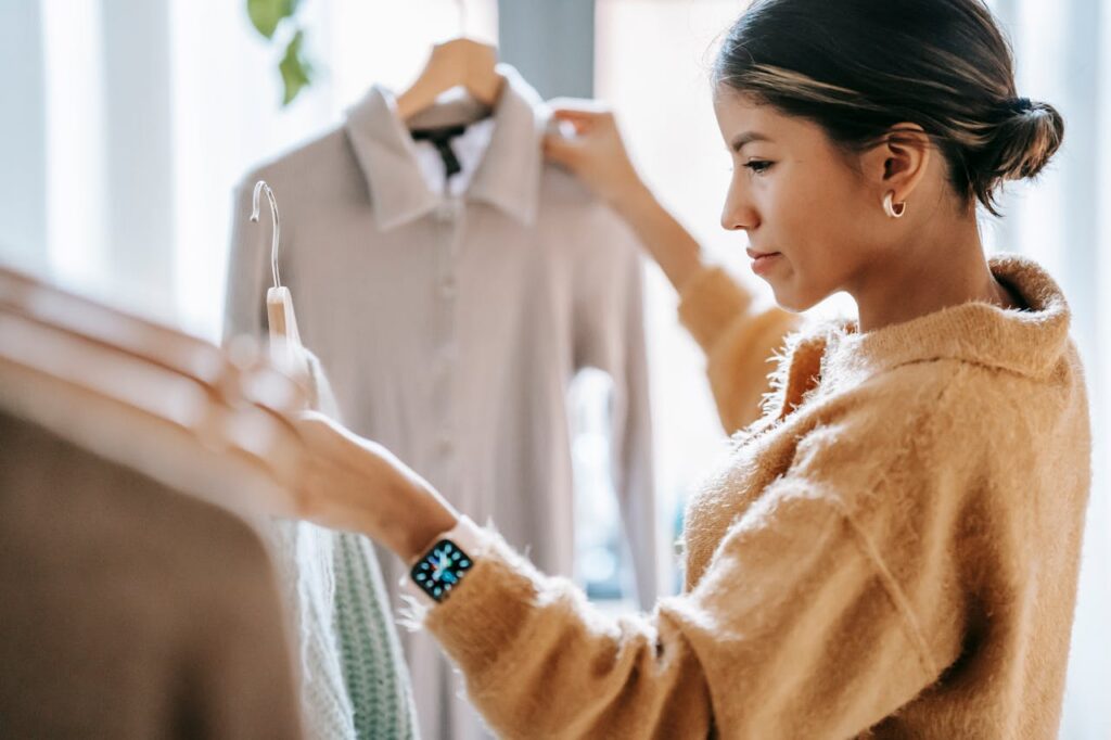 pexels photo 6347538 Crop focused ethnic female in casual clothes choosing apparel while standing near rack in boutique